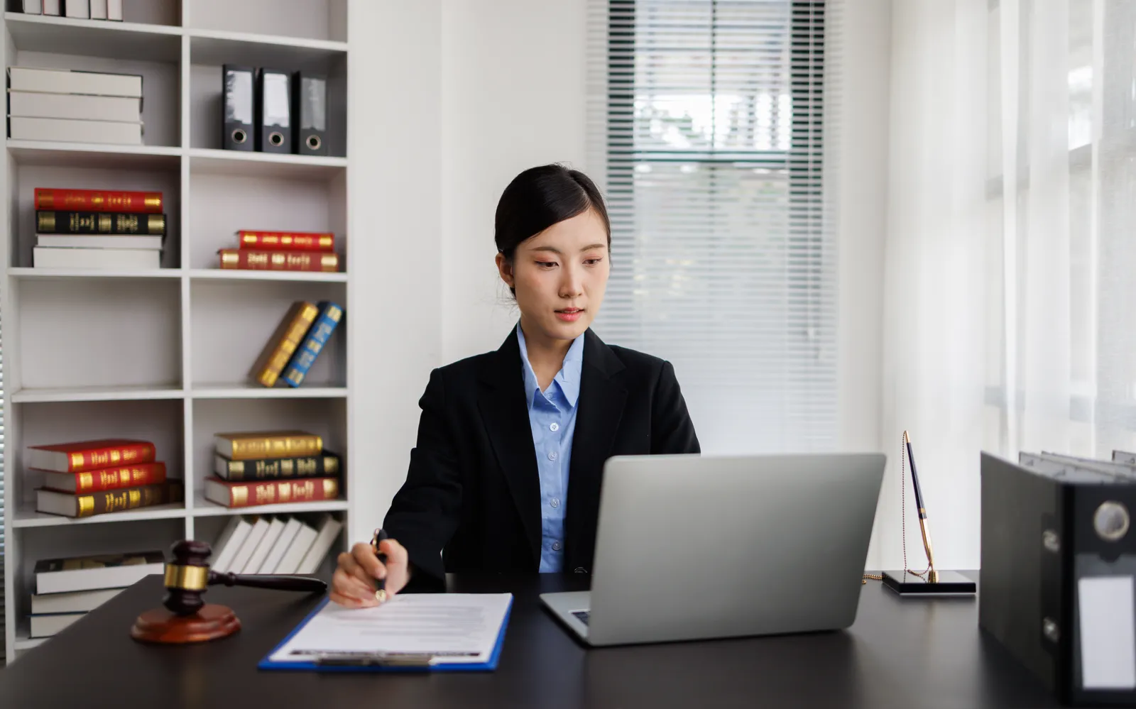 Attorney at a desk with a laptop and printed pages, checking an AI-drafted demand letter against the case file