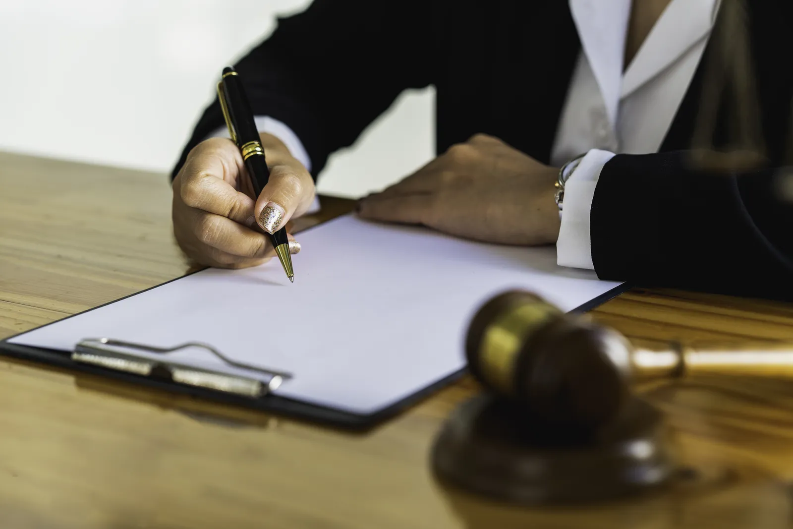 Attorney signing a final document at a desk with a gavel, representing the lawyer's sign-off on an AI-assisted demand