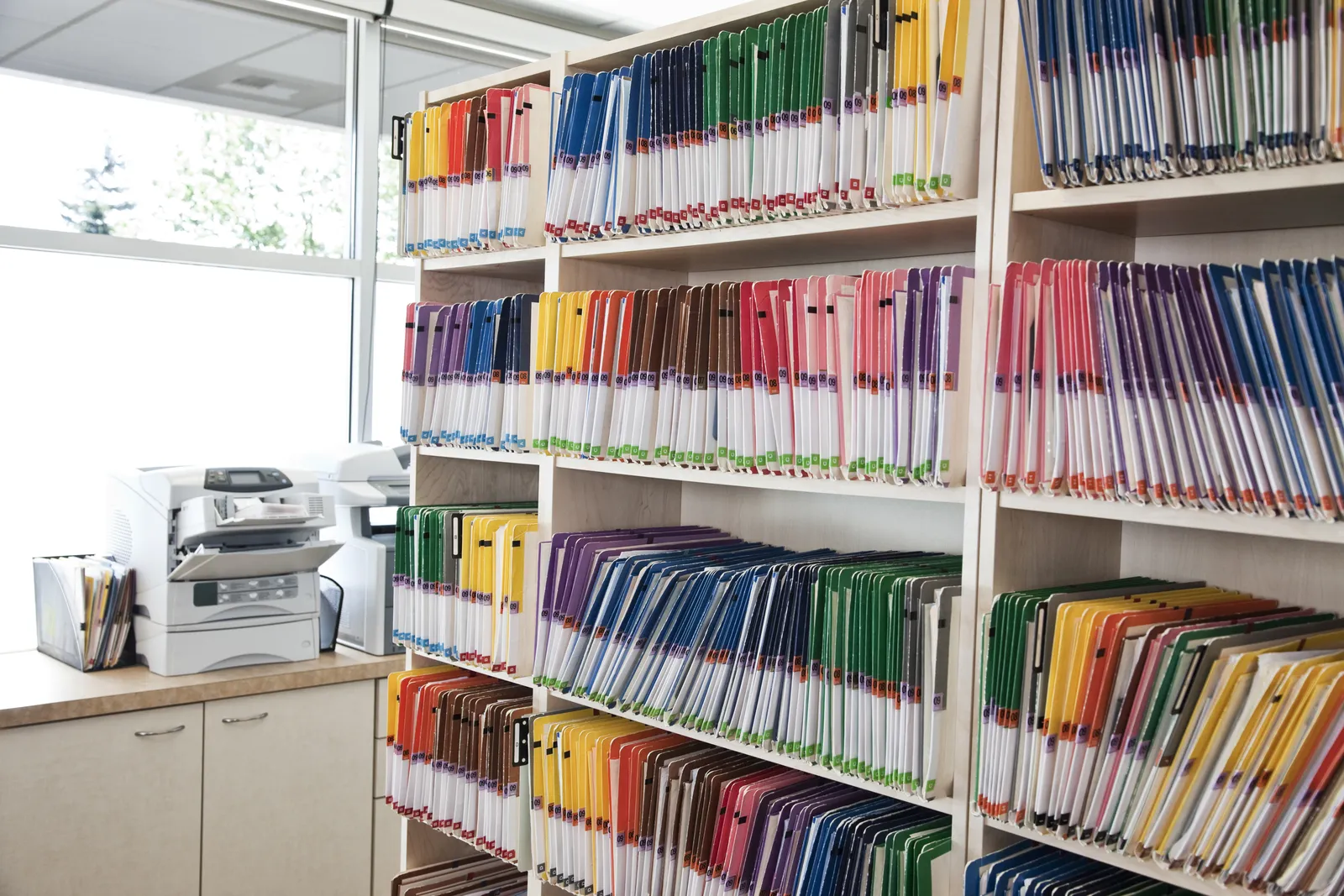 Shelves of color-coded case files in a personal injury law firm office, the records AI tools sort and extract