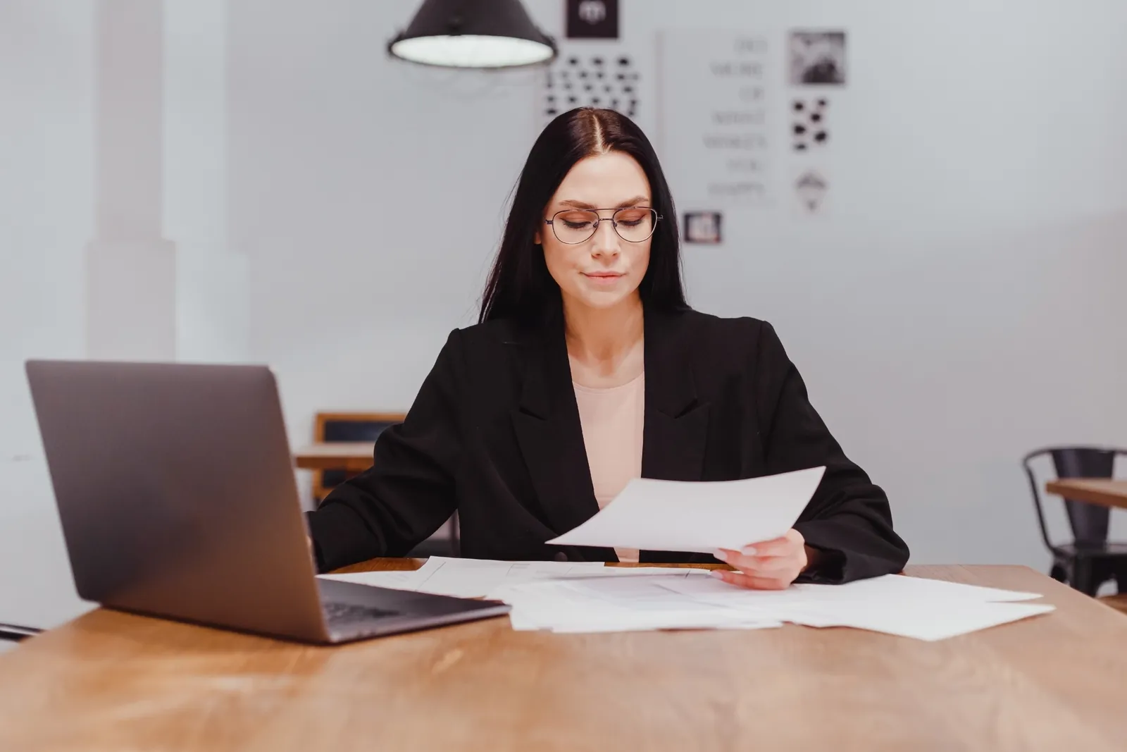 Paralegal comparing printed medical records with an AI medical chronology on a laptop