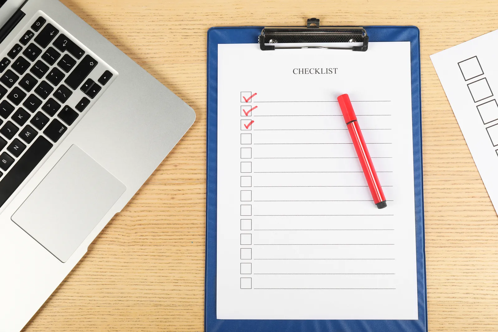 Checklist on a clipboard next to a laptop for evaluating medical chronology software