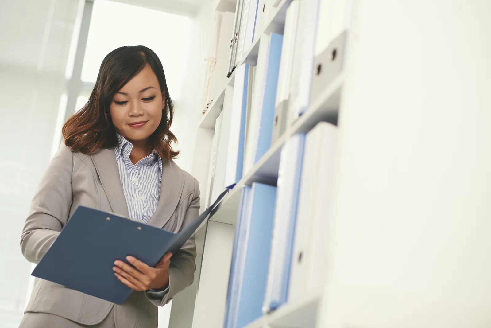 Legal assistant pulling a binder of medical records from a shelf to build a manual medical chronology