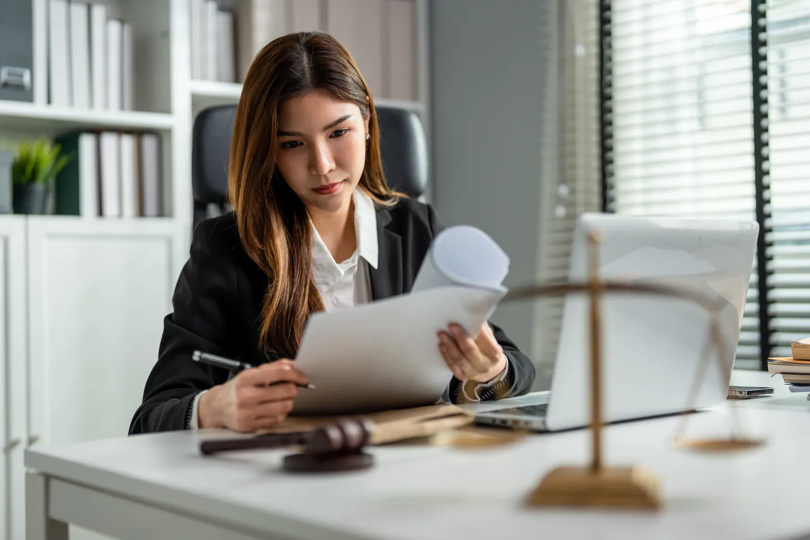 Attorney at a desk reviewing a settlement offer document next to scales of justice and a gavel