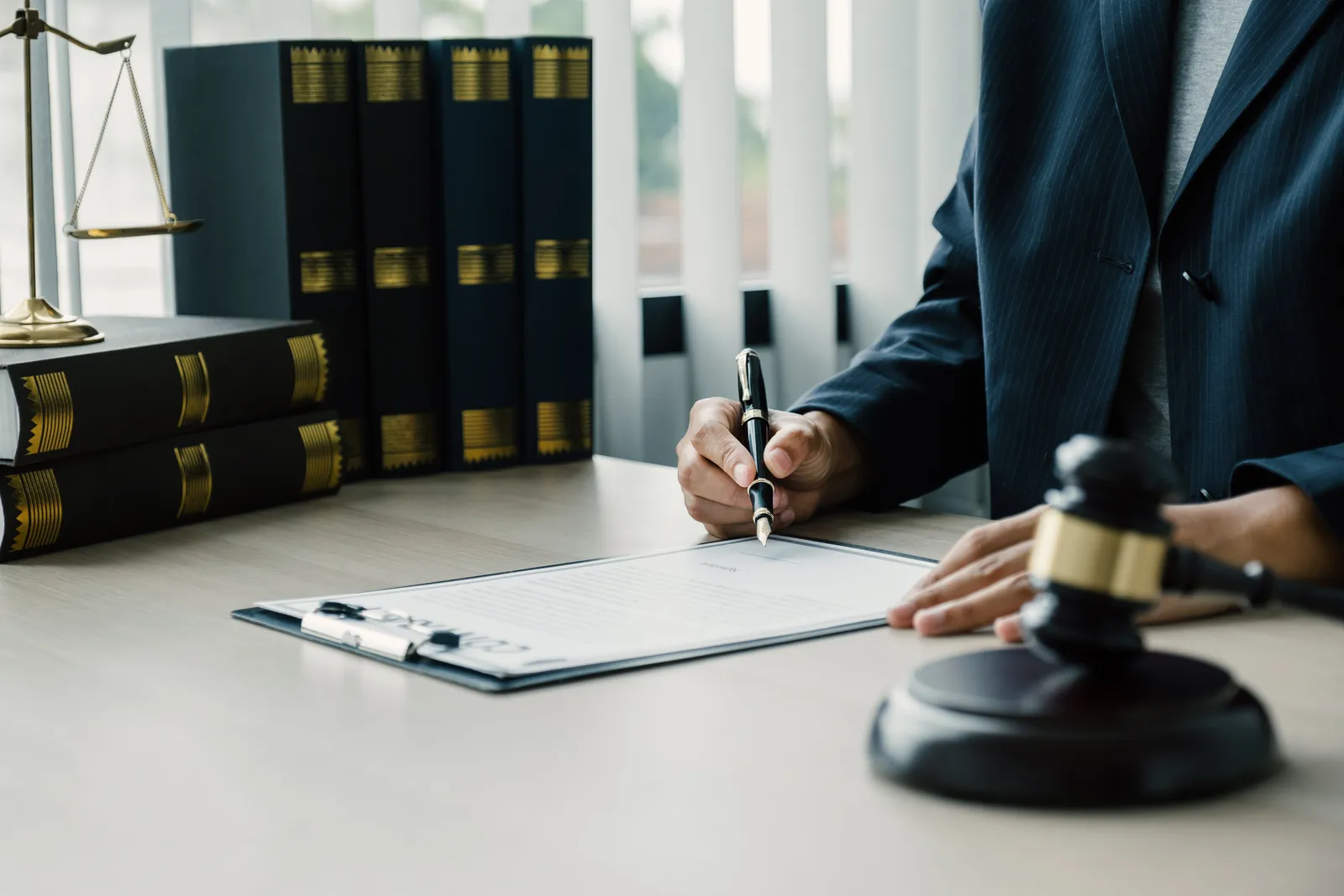 Attorney signing a settlement offer document on a desk next to a gavel and law books
