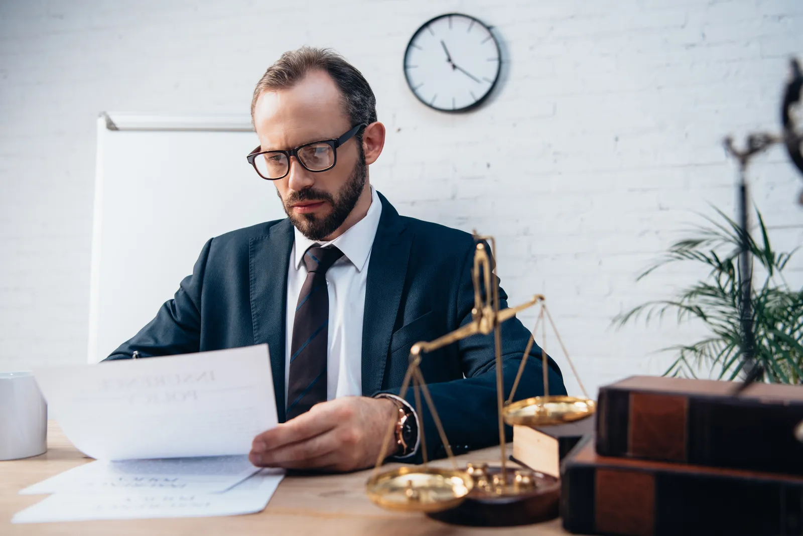 Attorney reading an insurance policy at a desk before drafting a demand letter to the insurance company