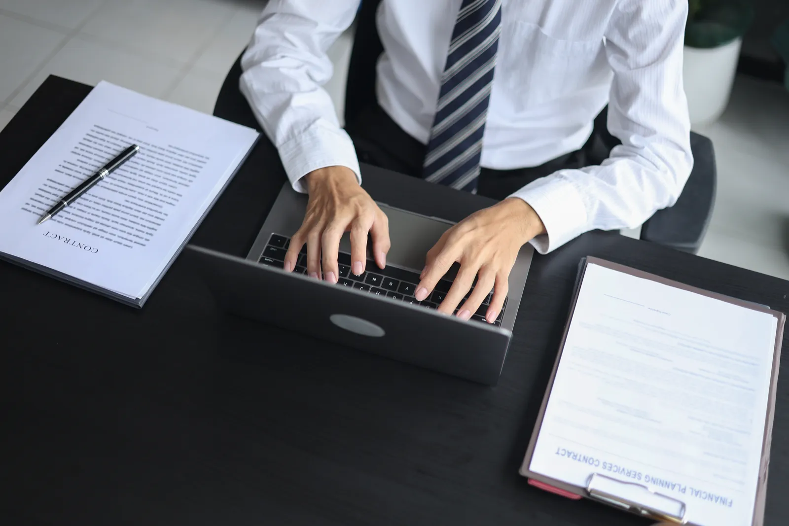 Paralegal typing a bodily injury demand letter on a laptop with the medical records and bills beside it