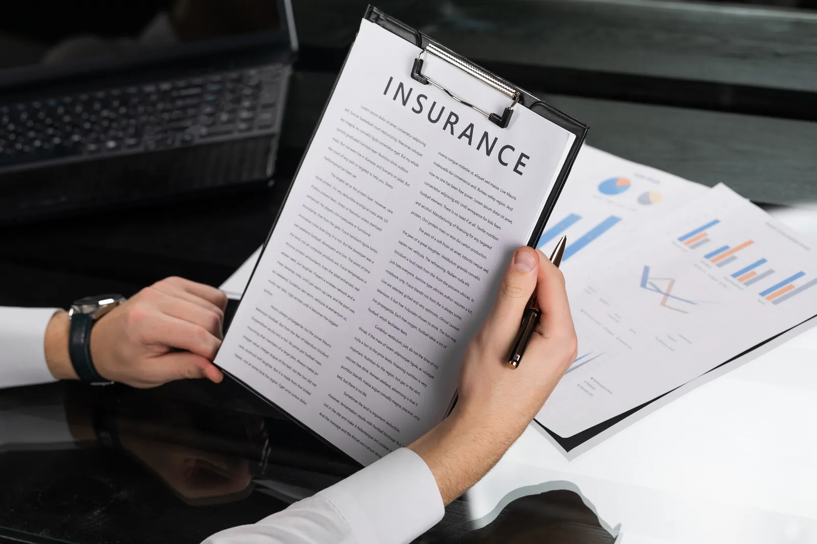 Insurance adjuster reviewing a bodily injury demand package on a clipboard with claim charts on the desk