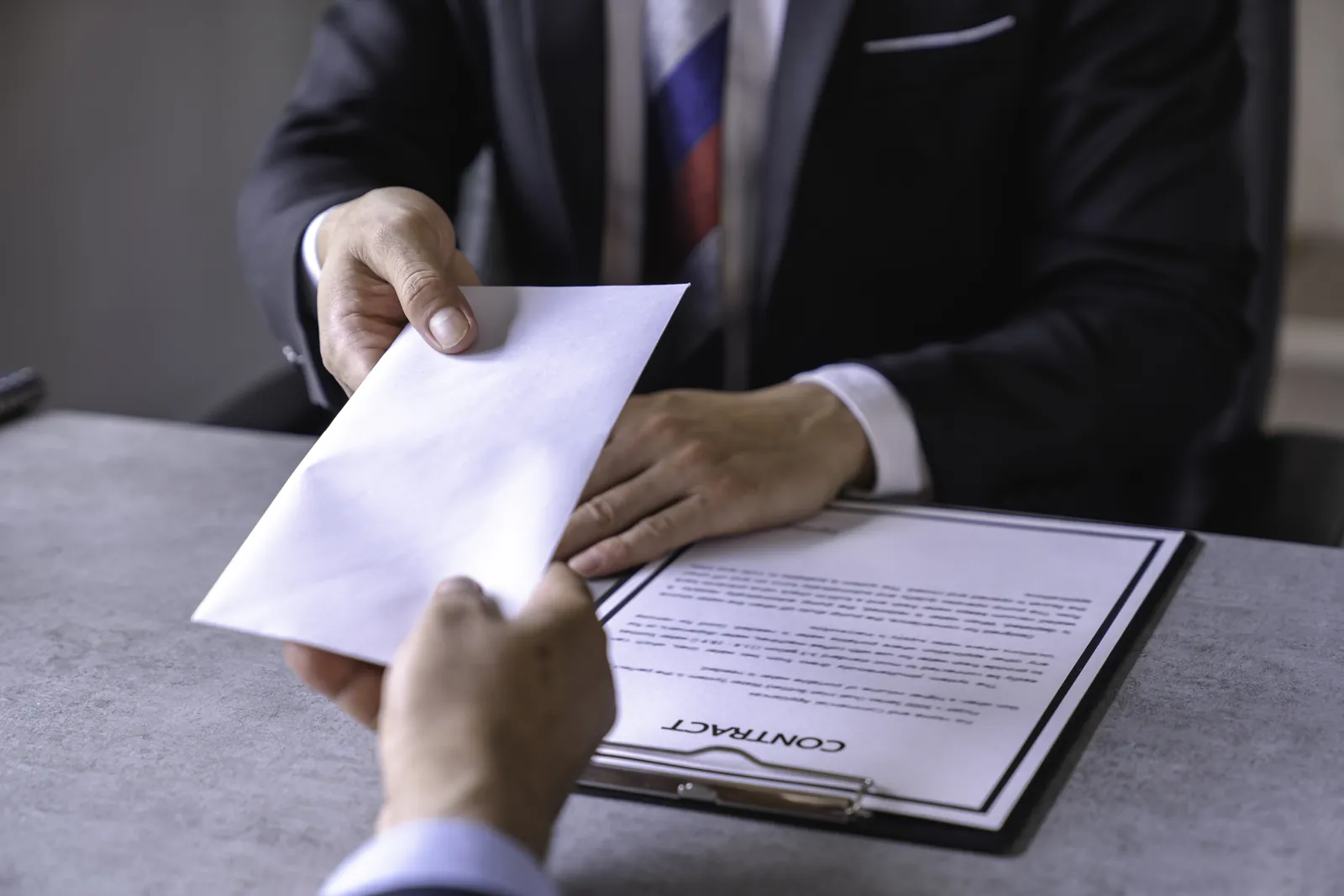 Attorney handing over an envelope containing a demand letter to the insurance company across a desk