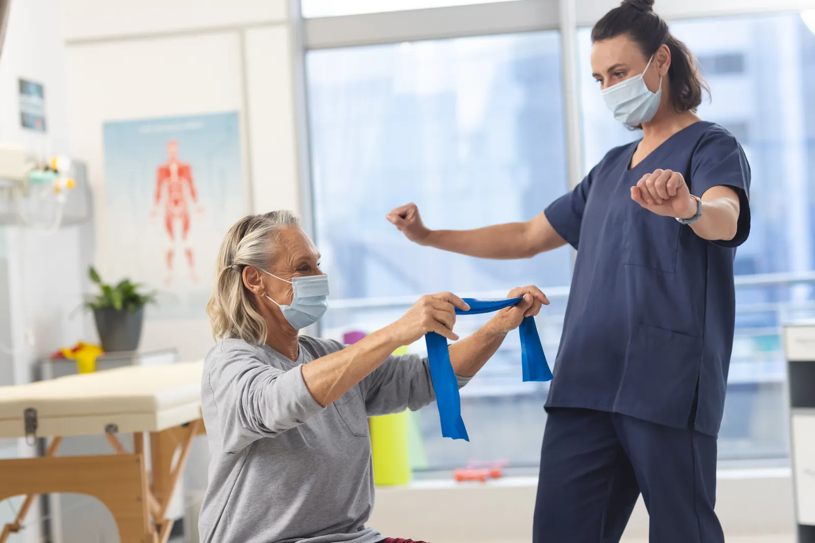 Older woman doing resistance band exercises with a physical therapist in a clinic