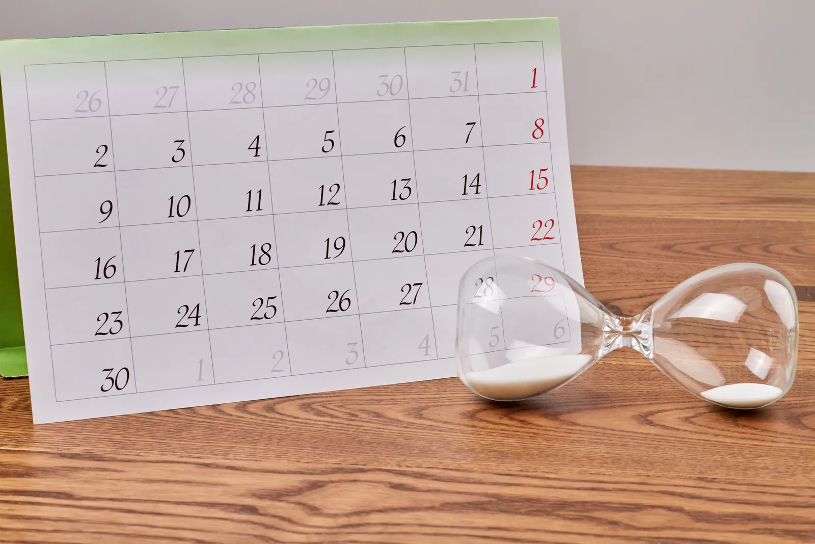 Hourglass next to a calendar on a wooden table, representing medical record retention periods running out