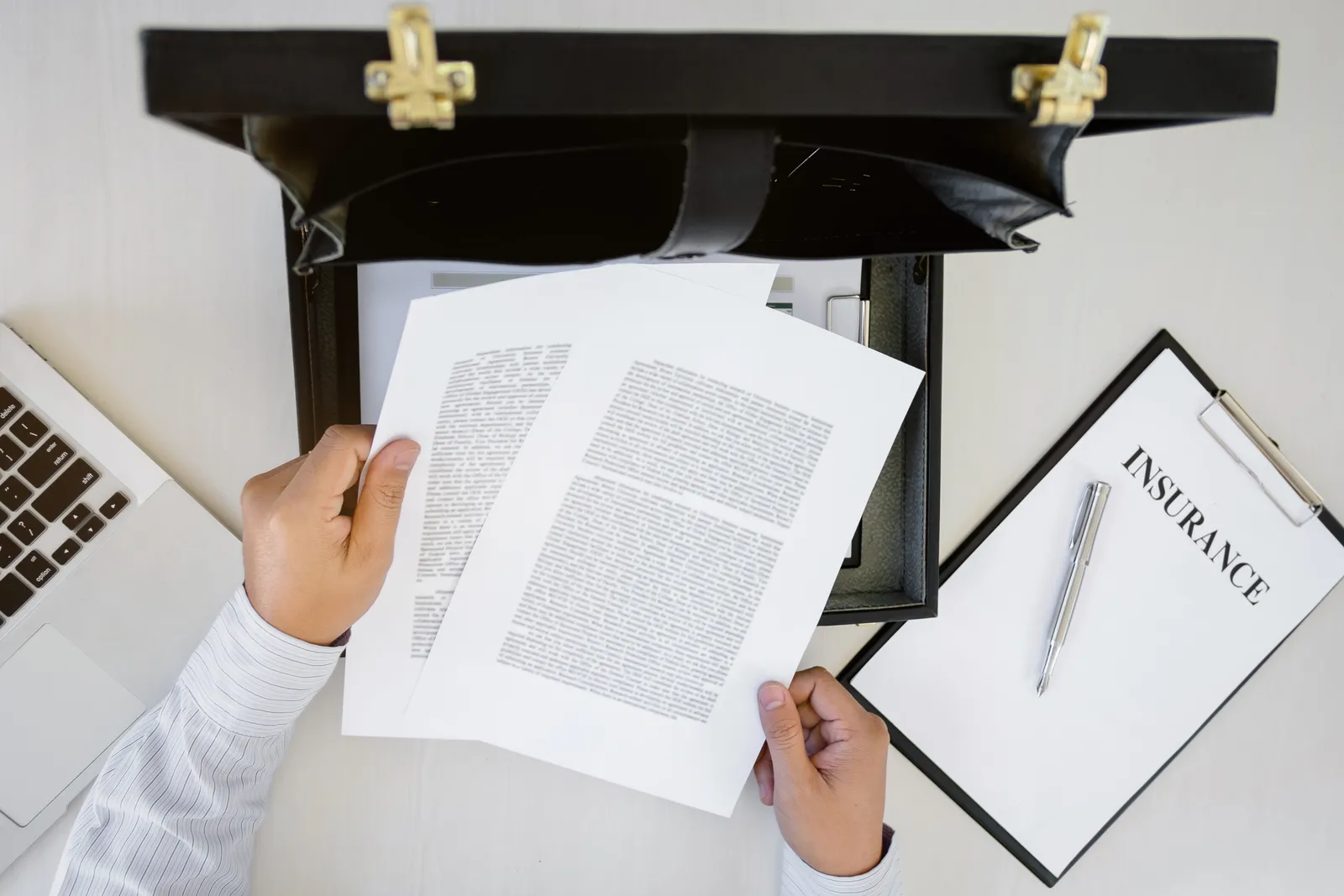 Attorney reviewing printed insurance documents next to a clipboard labeled insurance