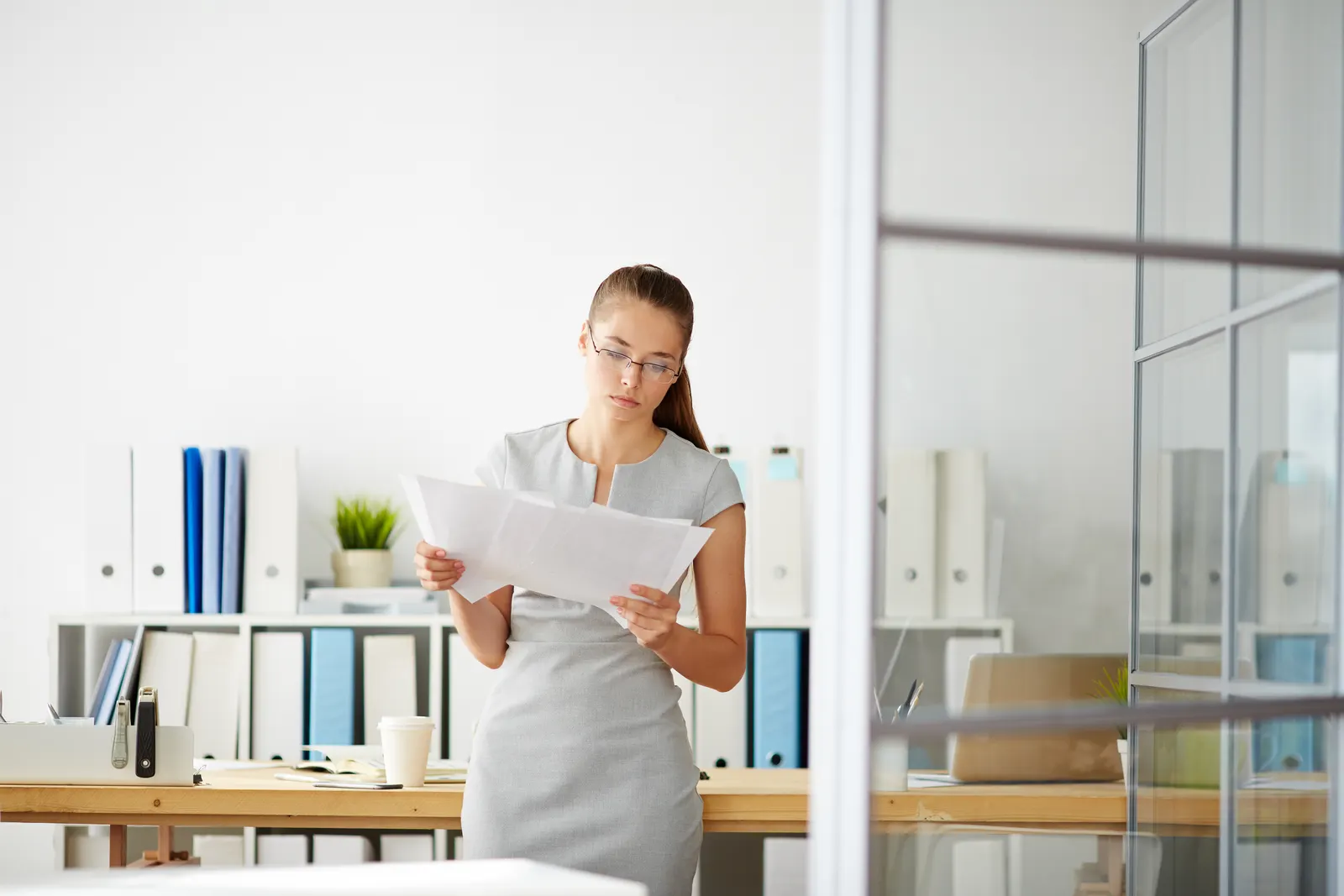 Professional reviewing documents at her desk while checking medical chronology entries against the source records
