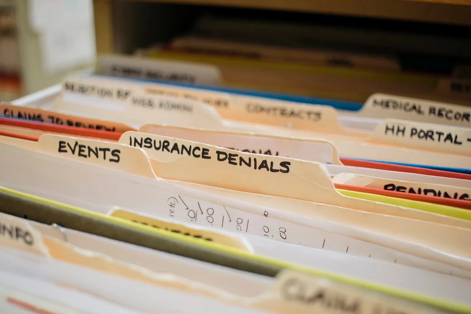 Labeled file folders for medical records and insurance paperwork in a law firm filing drawer