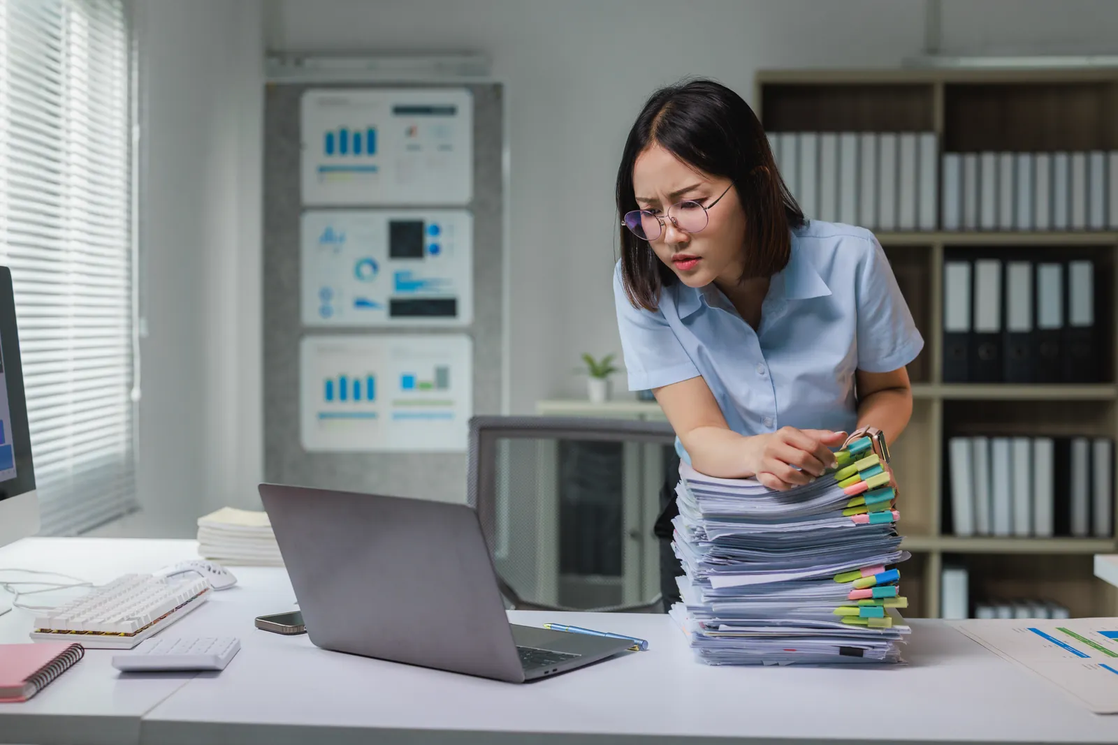 Paralegal sorting a tall stack of tabbed medical records for a personal injury medical record review