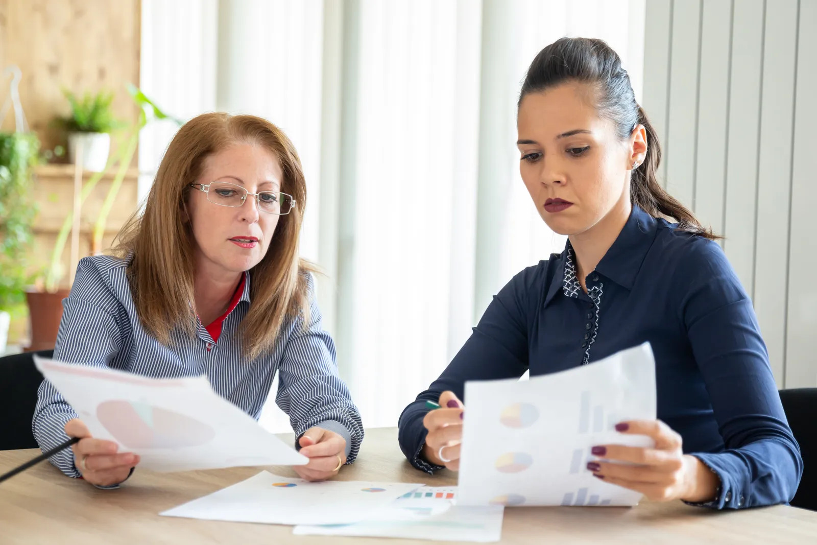 Two paralegals comparing printed pages at a desk while checking a medical chronology returned by a review service