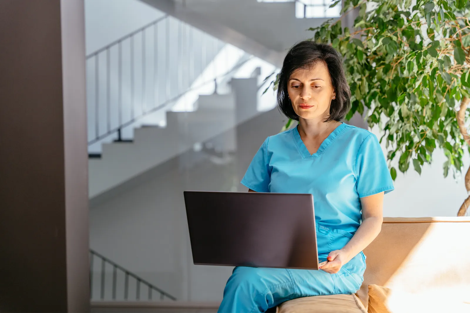 Nurse in scrubs reviewing medical records on a laptop for a medical record review service
