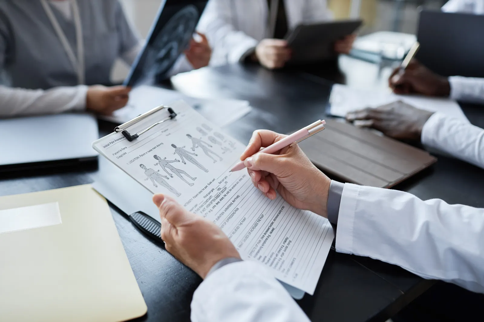 Physician marking up a patient form during a medical record review meeting with colleagues