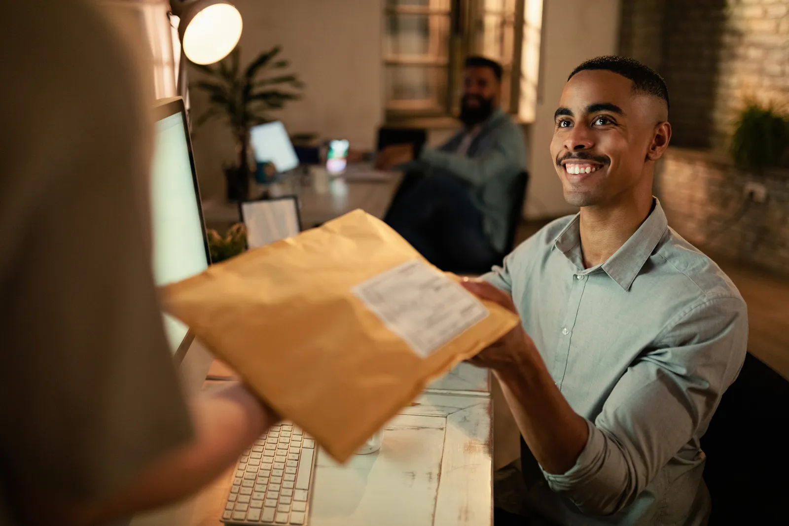 Paralegal handing a sealed envelope of medical records to a colleague for an outside medical record review service