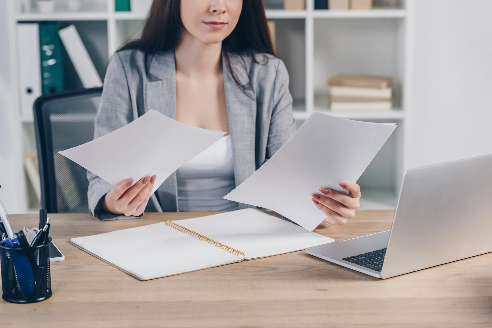 Paralegal comparing two printed pages side by side, checking a medical summary against the medical chronology