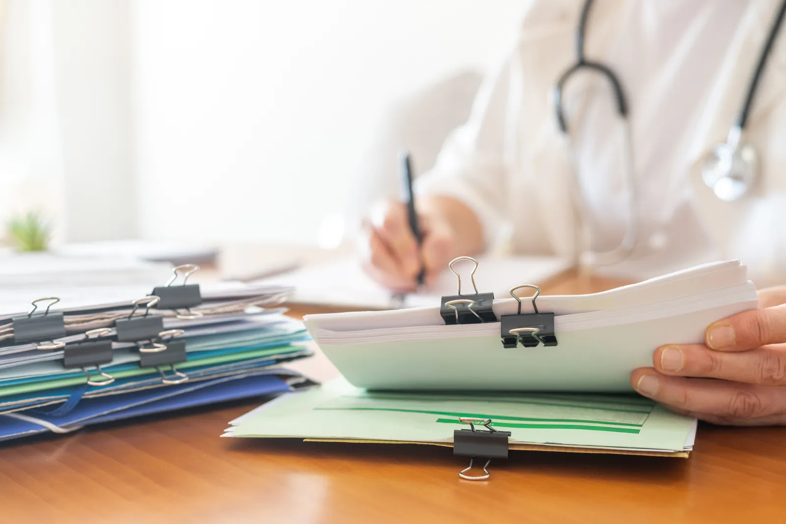 Stacks of clipped medical records on a desk, the source material for a personal injury medical summary