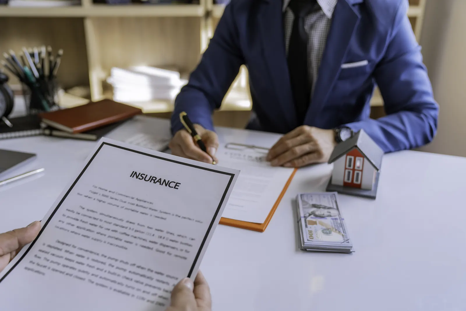 Professional signing insurance documents at a desk during a policy limits settlement