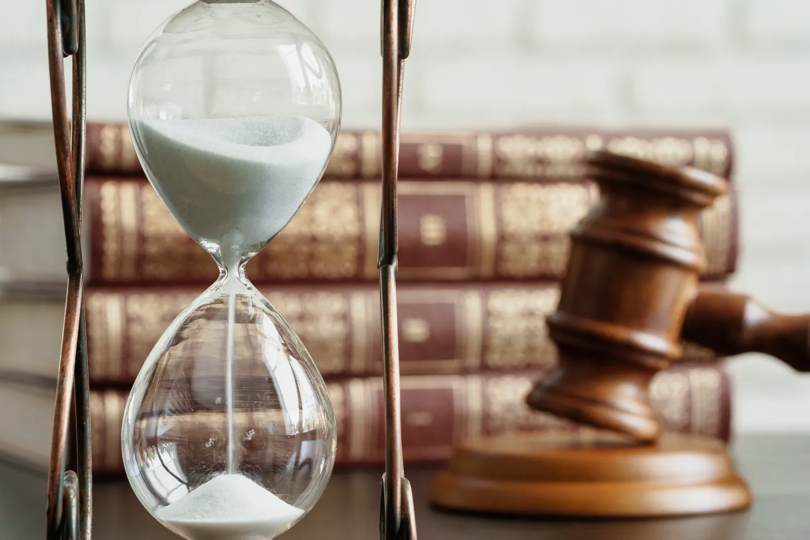 Hourglass next to a gavel and law books, representing the deadline in a time-limited policy limits demand